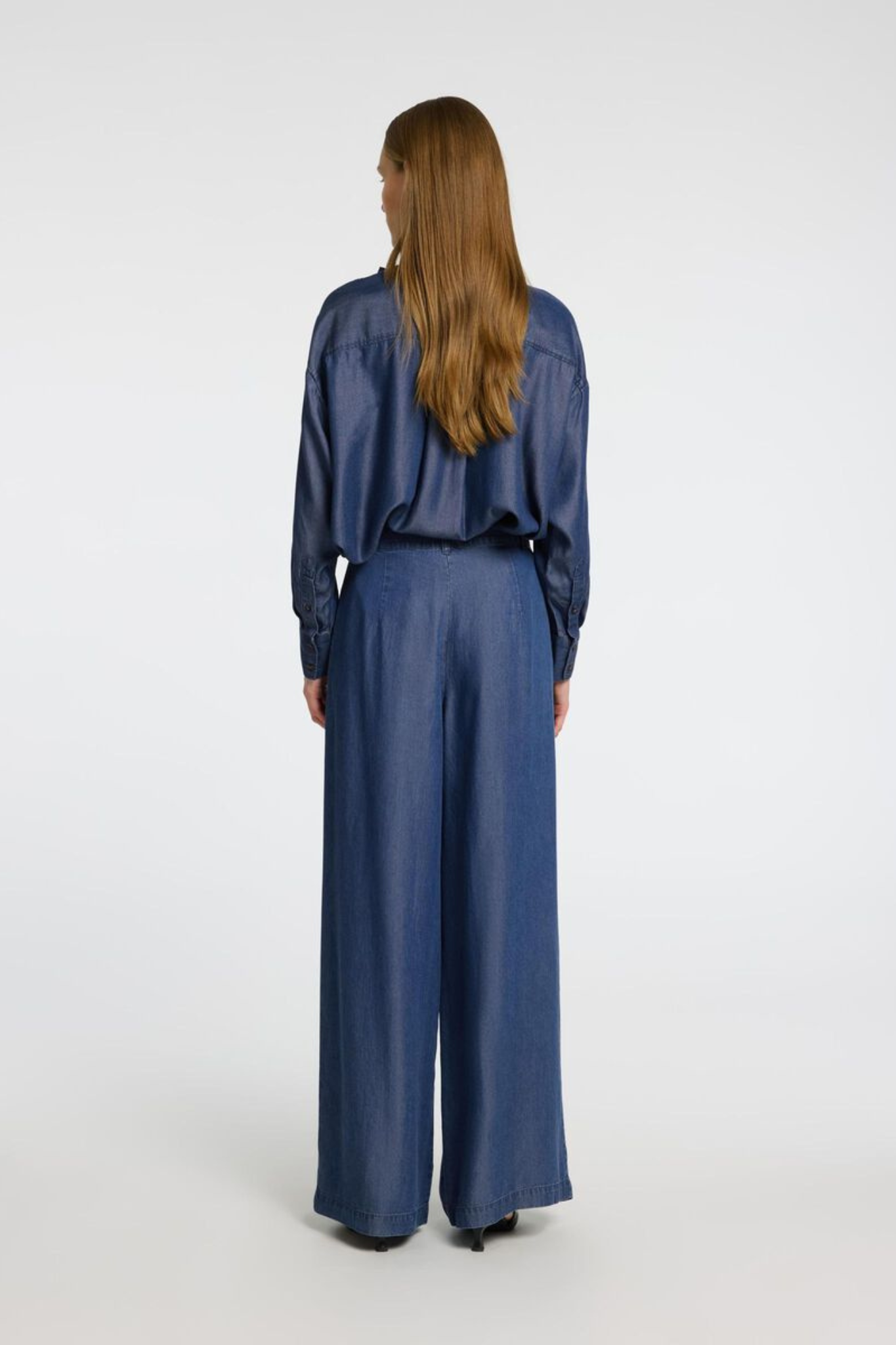 Model wearing the Selected Femme janna pleated chambray pants in dark blue. Back view