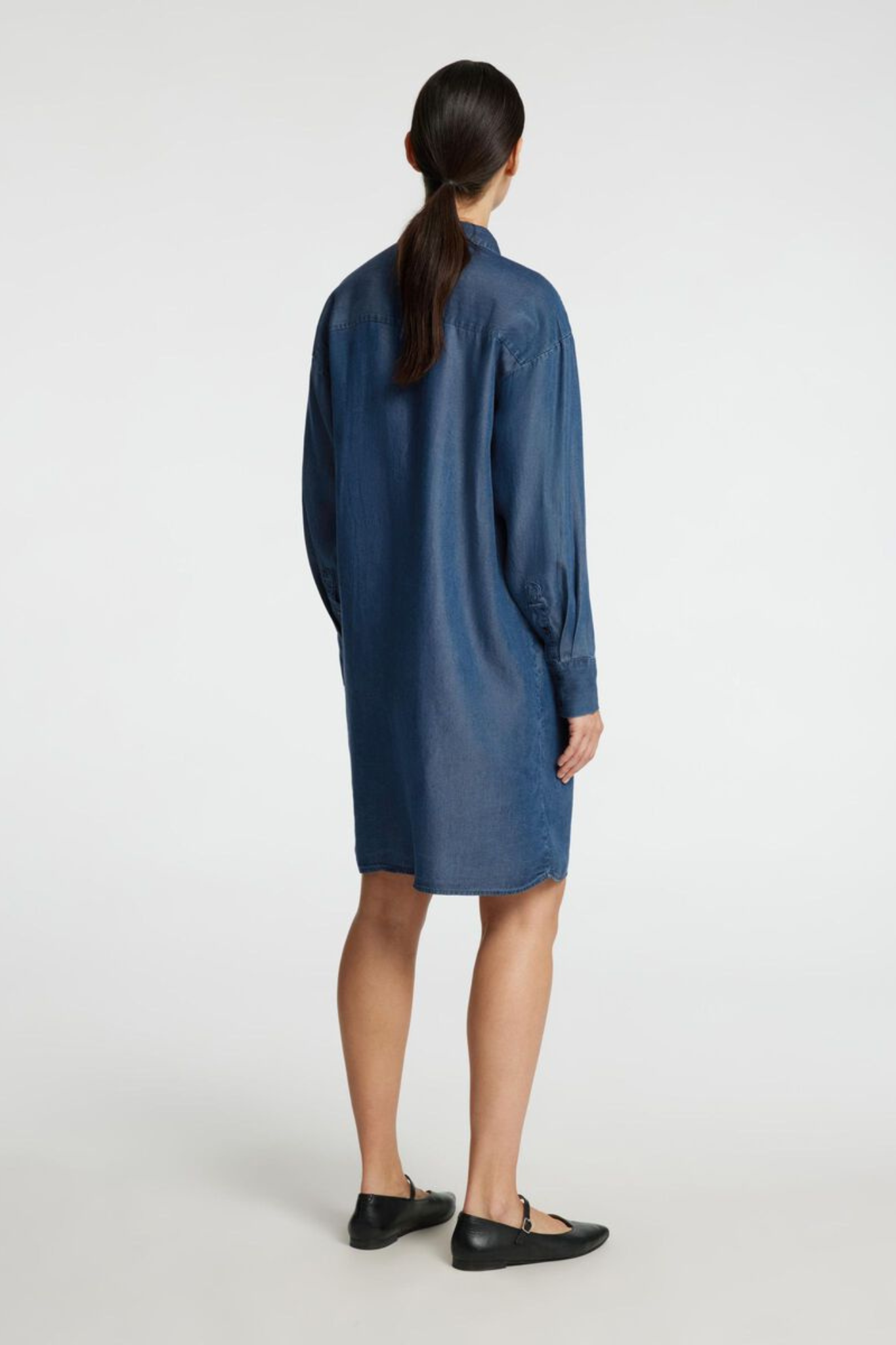 Model wearing the Selected Femme relaxed chambray shirt in dark blue denim. Back view