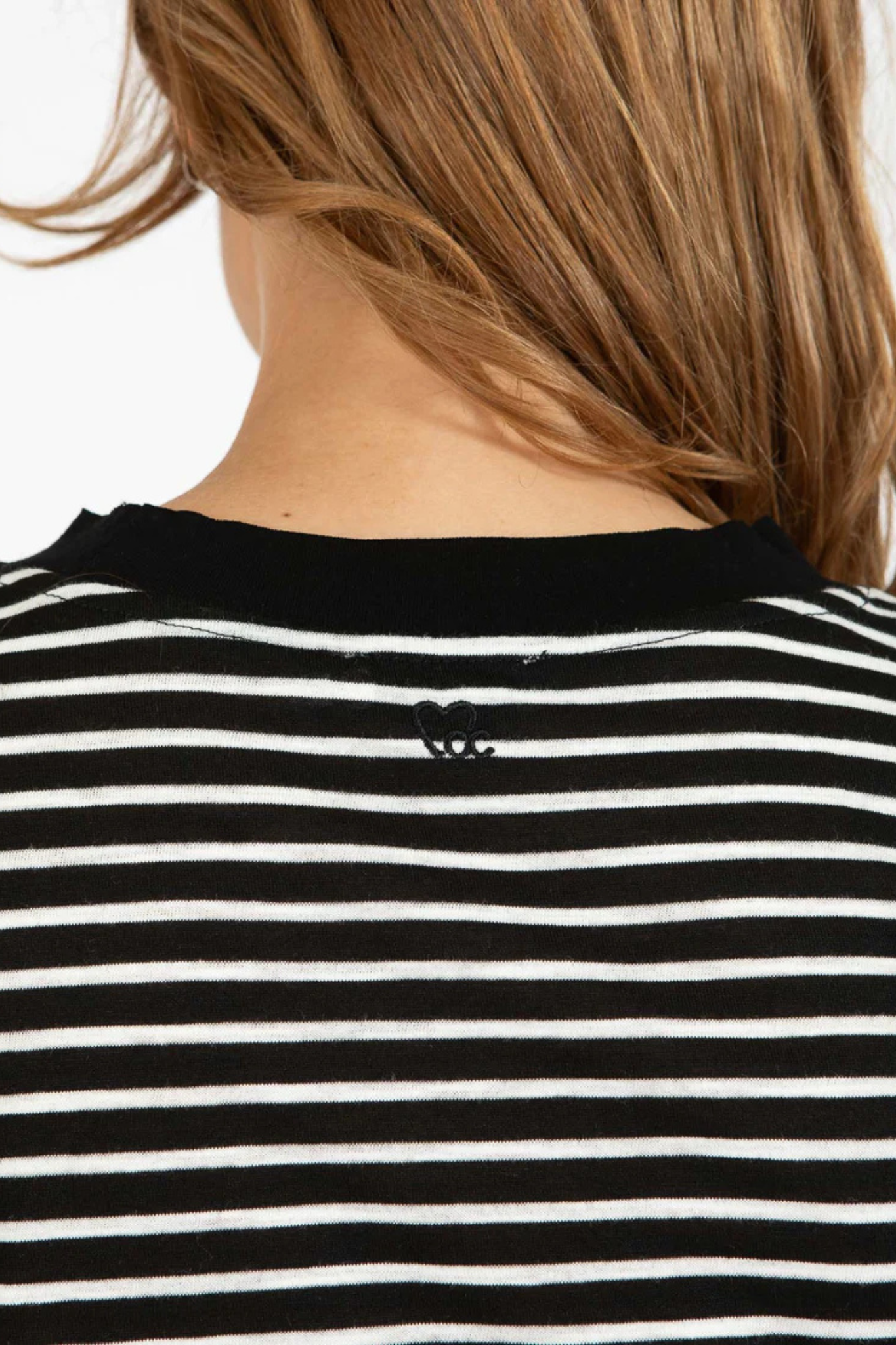 Model wearing the CC Heart silla stripe shirt in black and white. Close back view