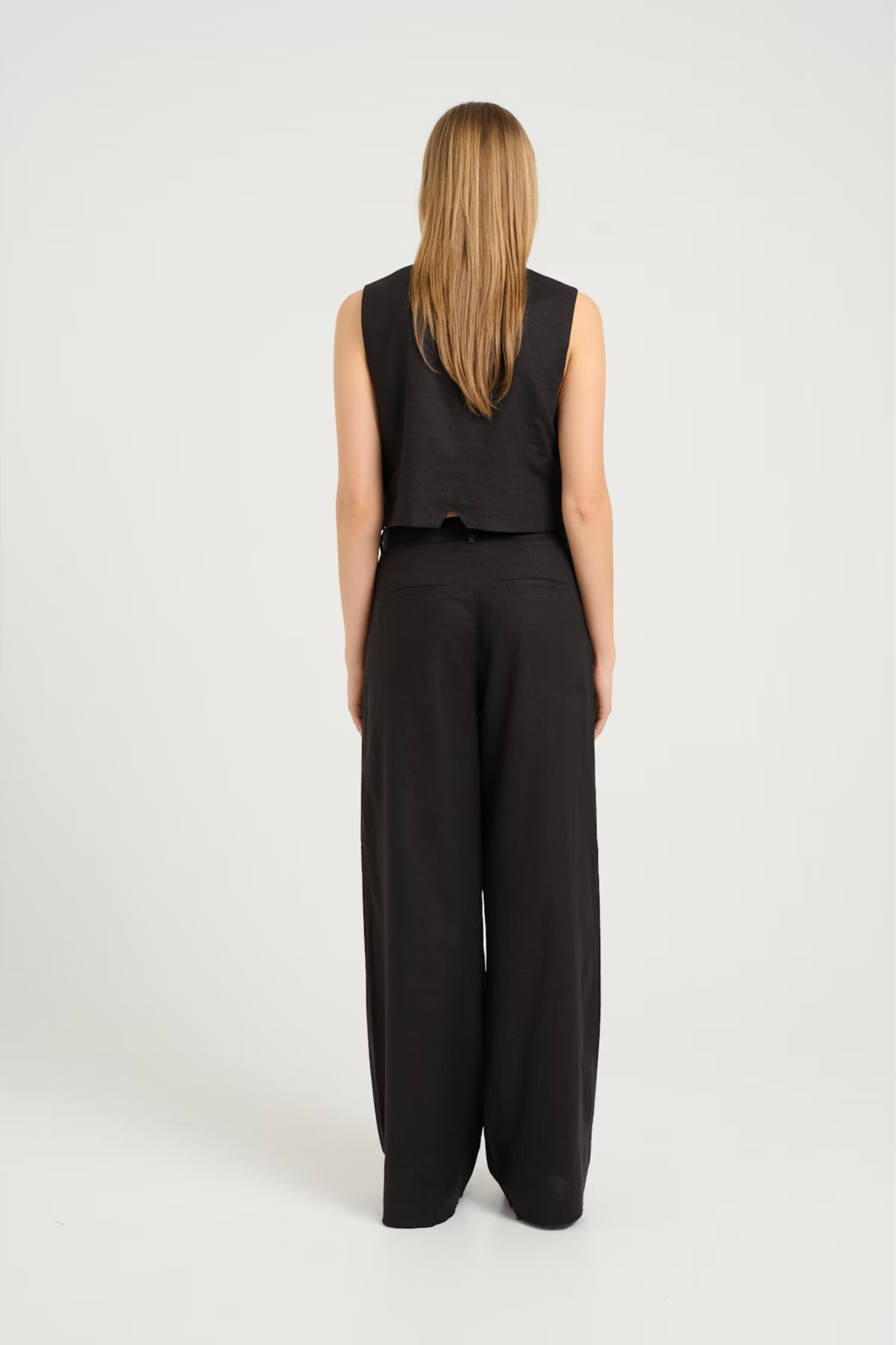 Model wearing the Gestuz elarah linen pants in black. Back view