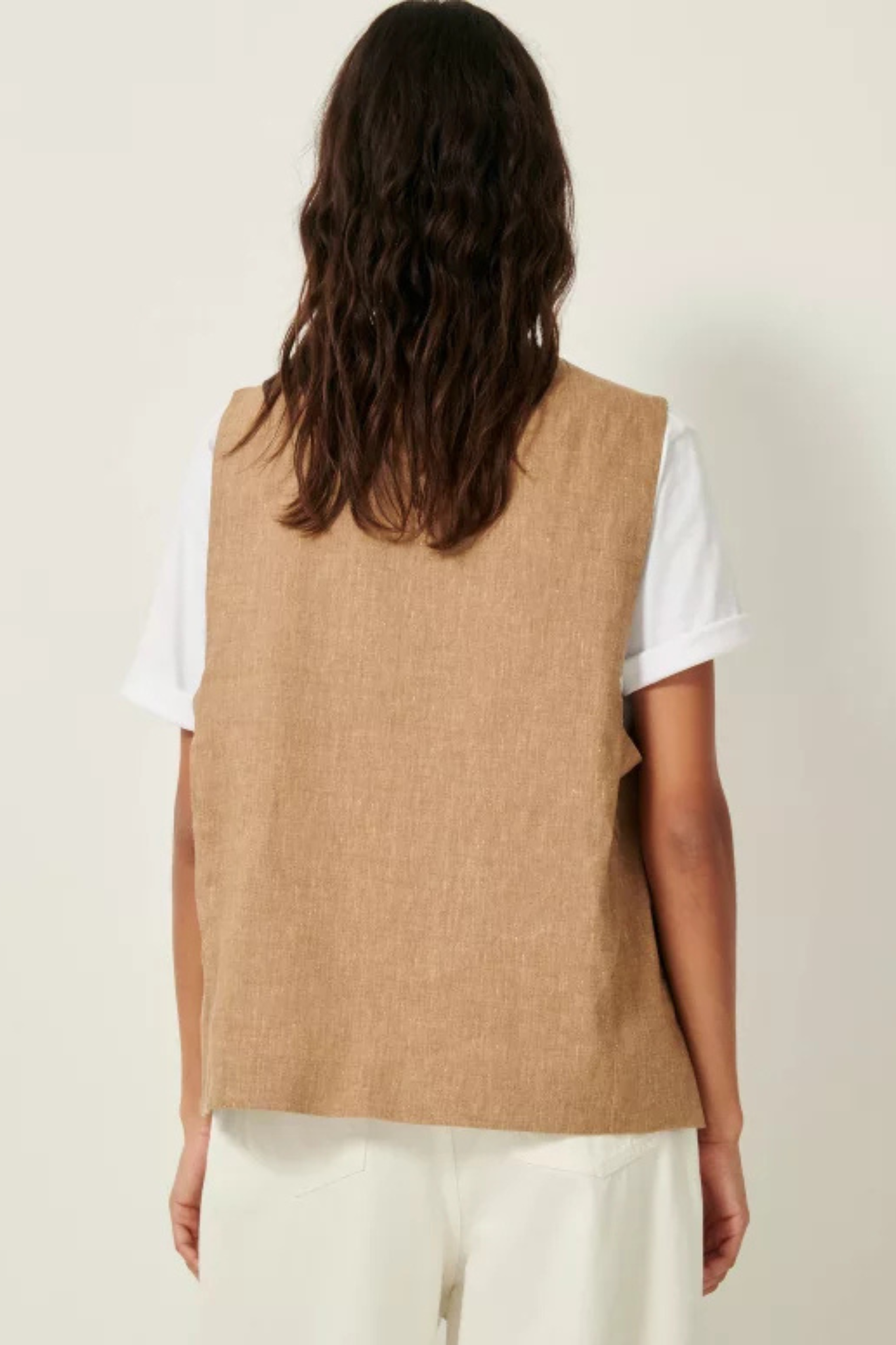 Model wearing the Sessun marcello sleeveless jacket in camel. Back view