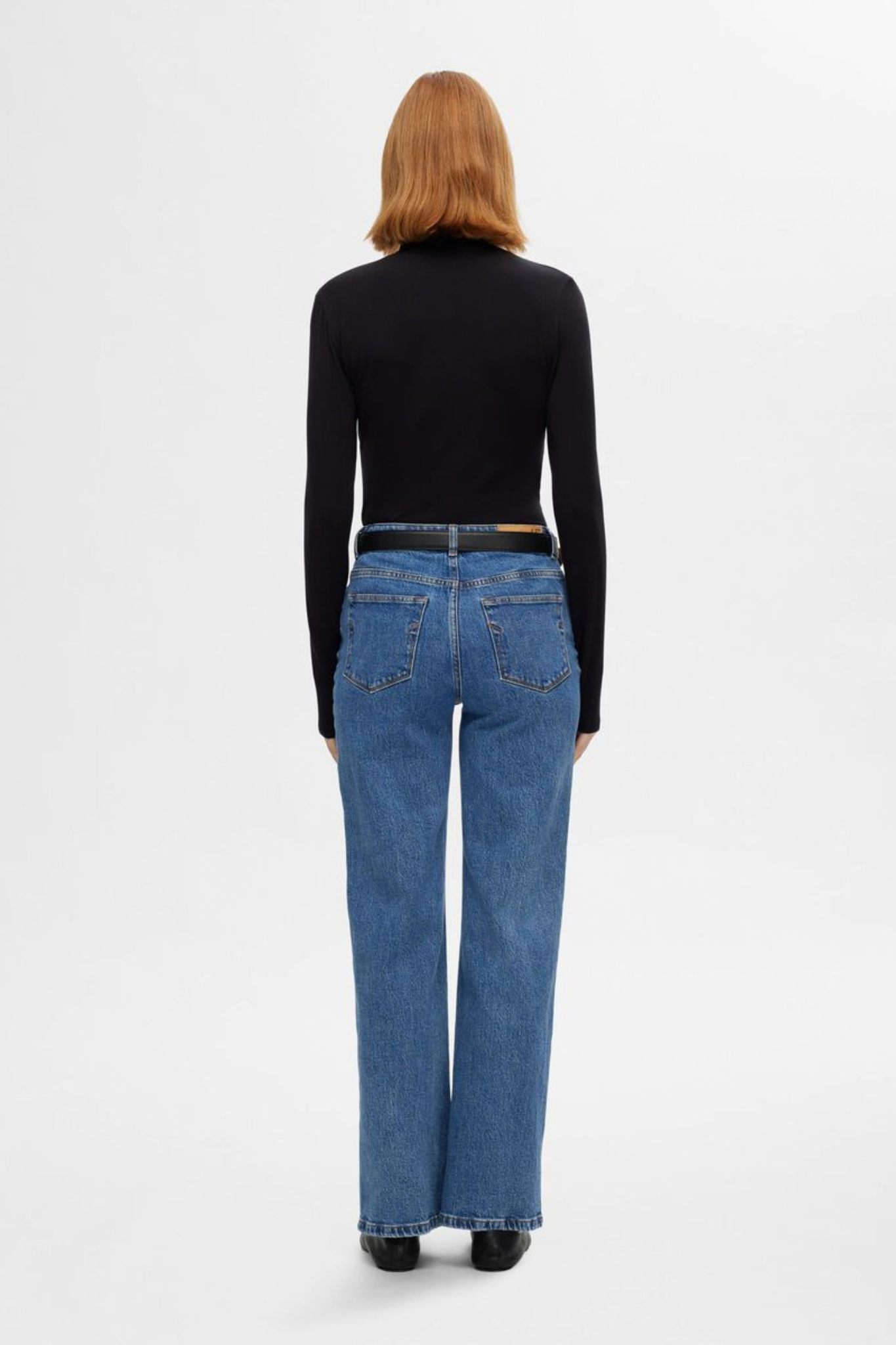 Model wearing the Selected Femme alice jeans hw wide long jeans in light blue denim. Back view