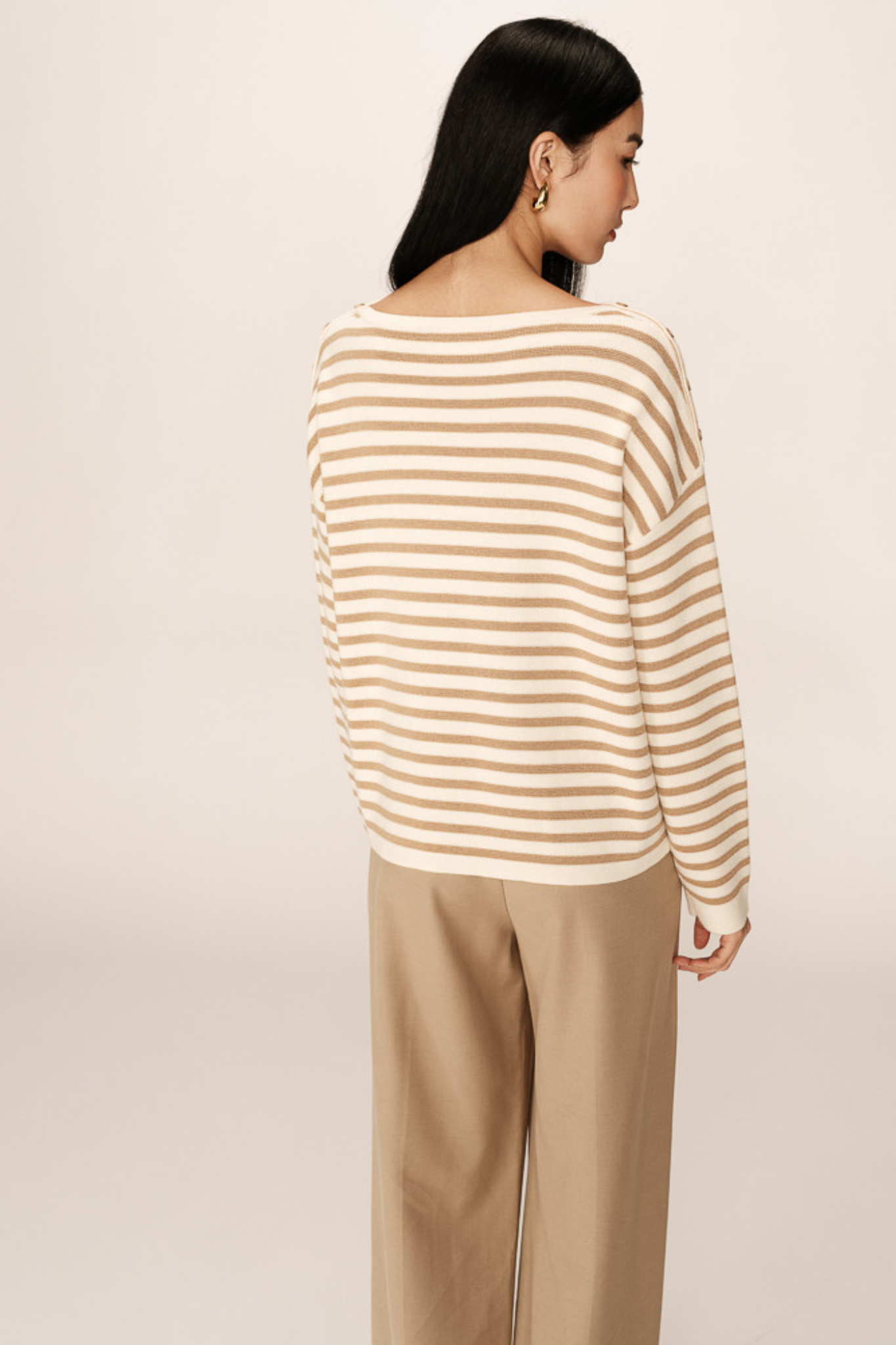 Model wearing the Grace & Mila pachamama sweater in gold and beige. Back view