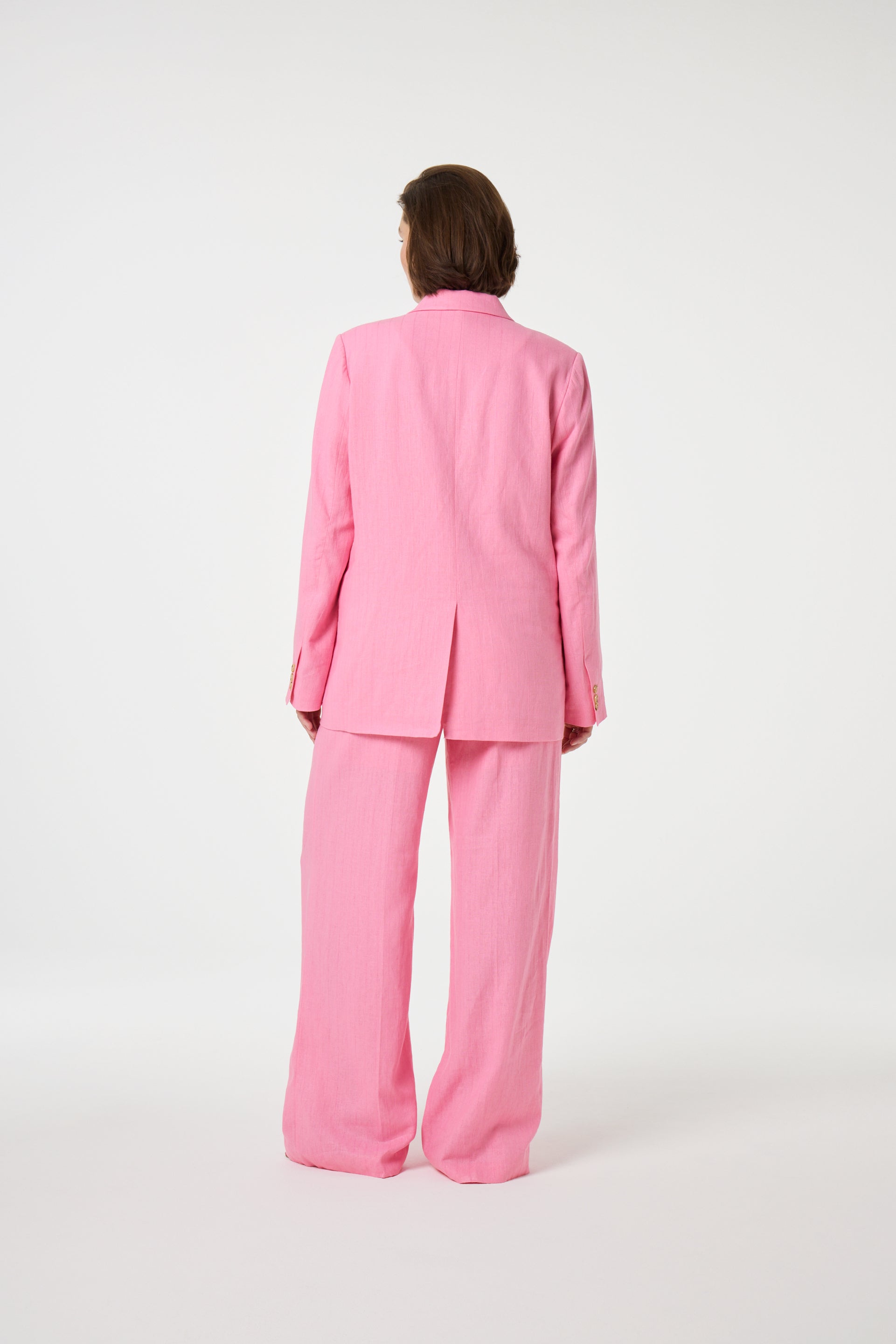 Model wearing the Fabienne Chapot nura pleated trousers in pink. Back view