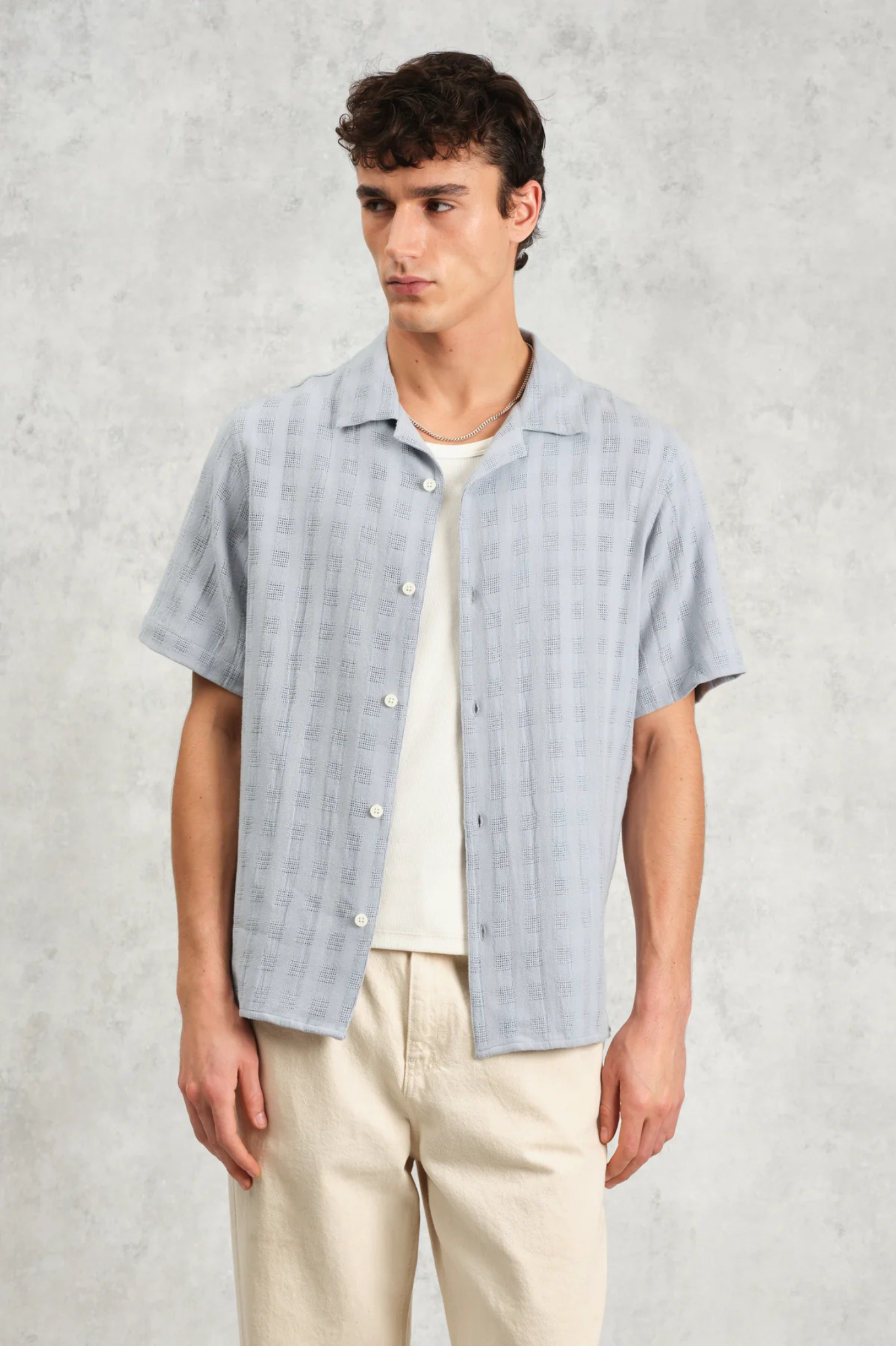 Model wearing the Wax London didcot box open weave grid shirt in pale blue. Front view 