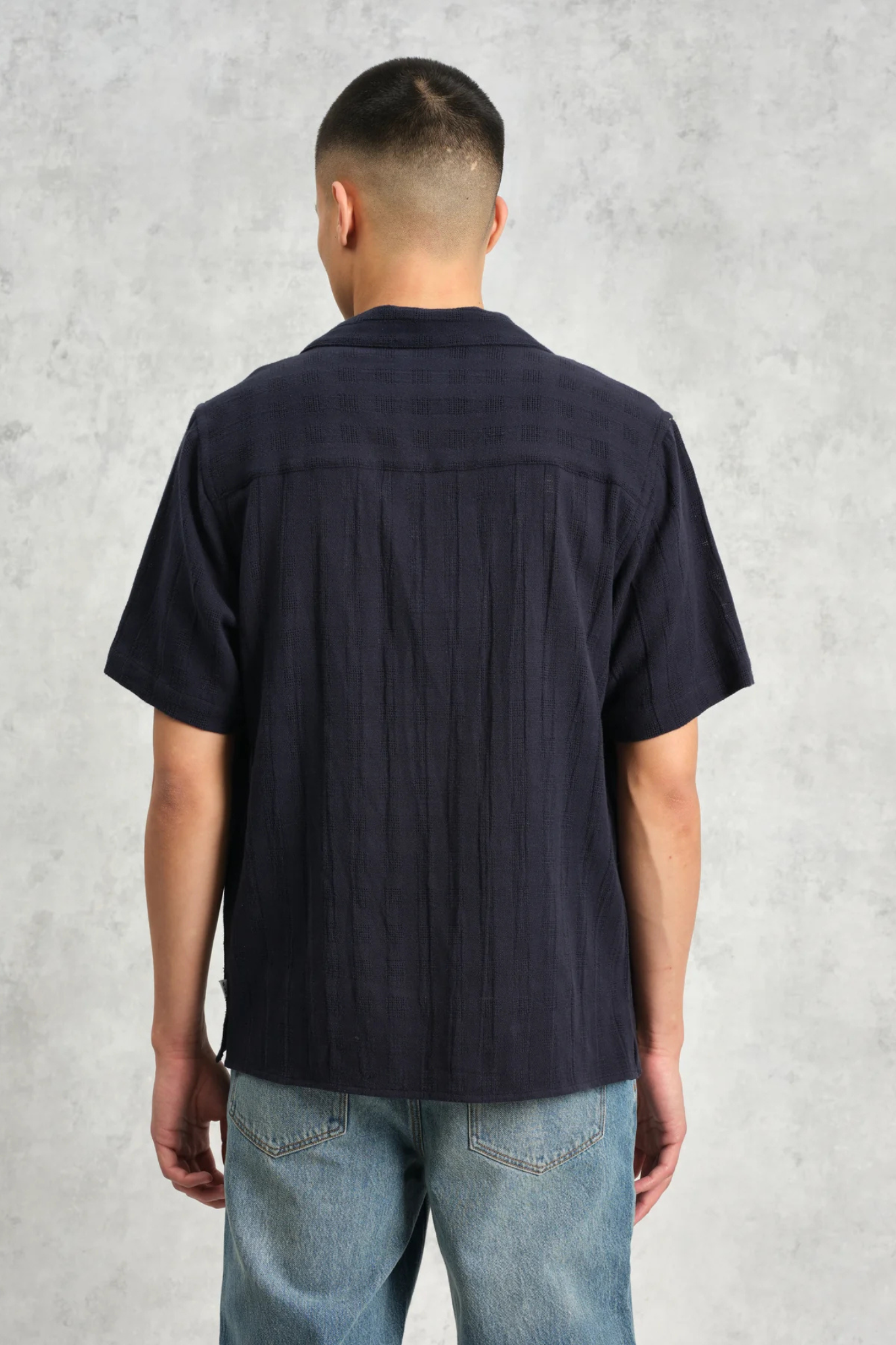 Model wearing the Wax London didcot box open weave grid shirt in navy. Back view 