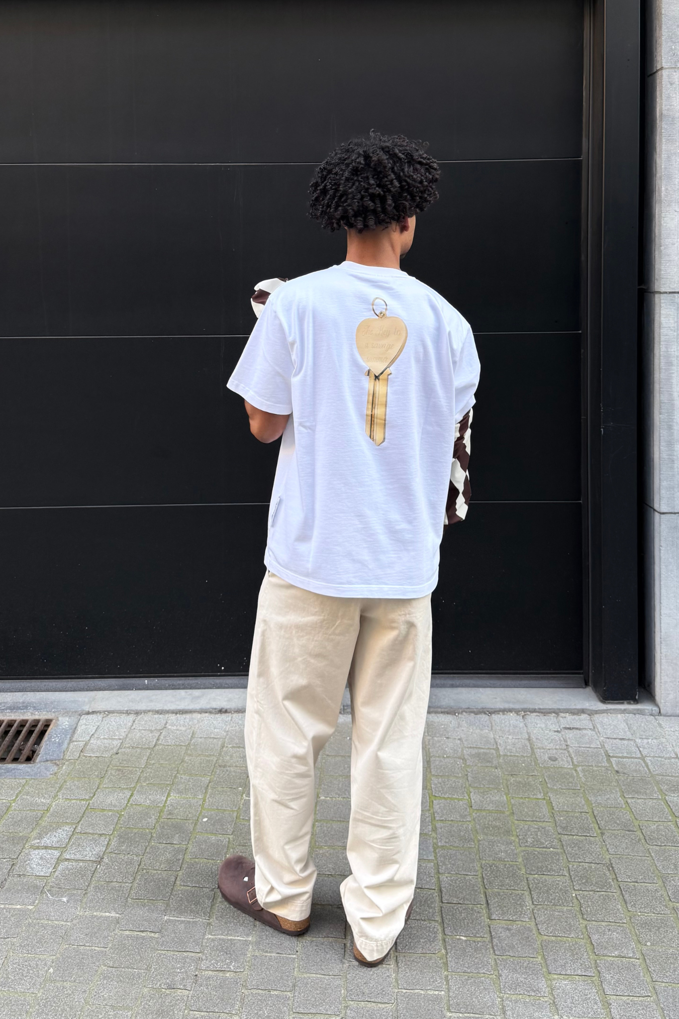 Model wearing The Savage Report key t-shirt in white. Back view